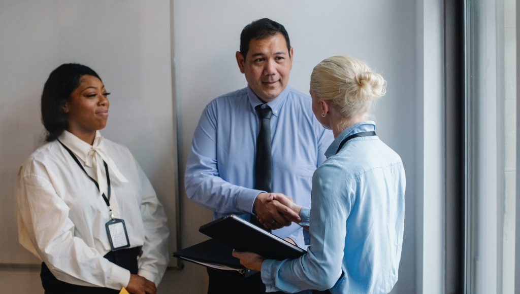 Three people standing in a business meeting.